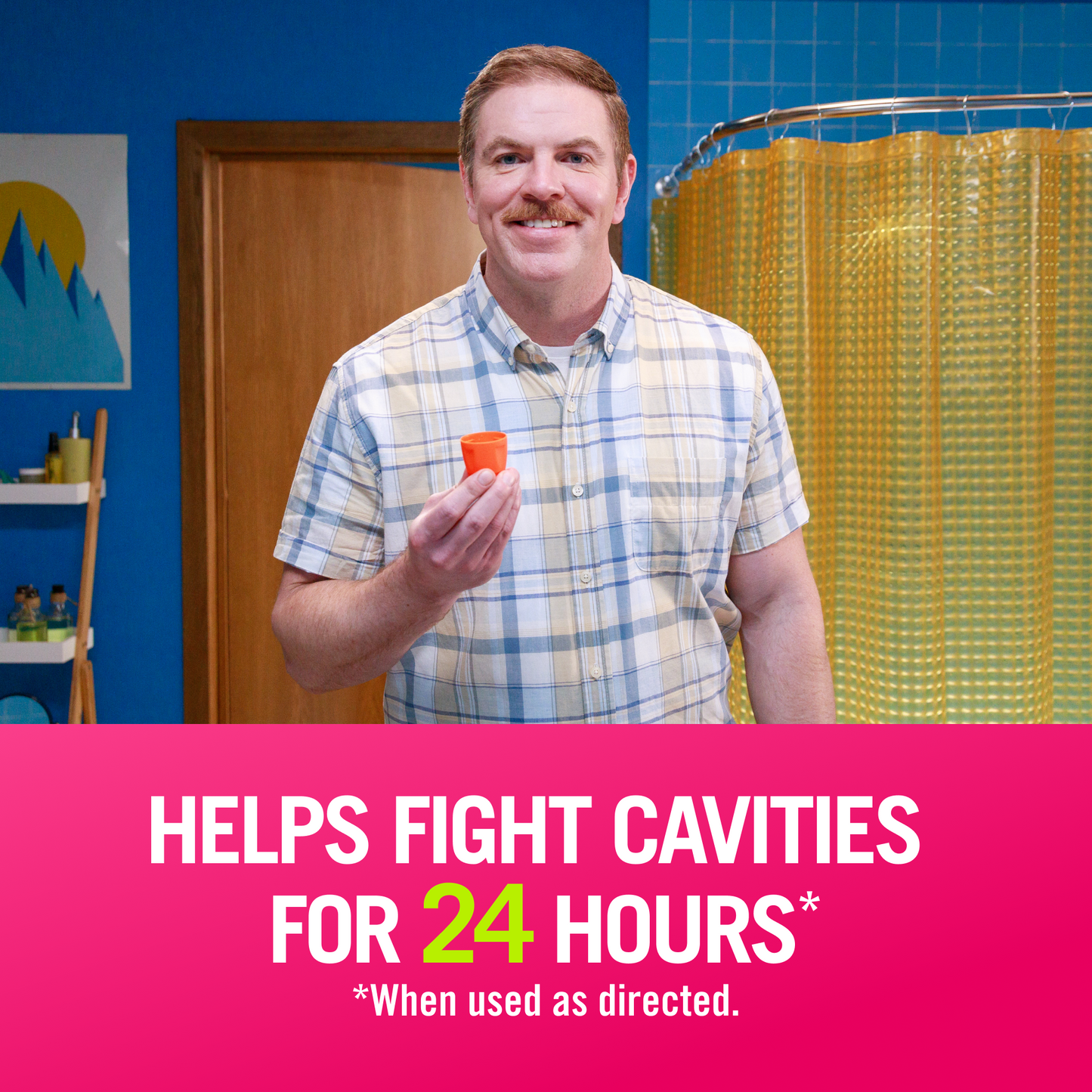 Man in blue bathroom leans towards the camera, smiling and holding a TheraBreath cap. "Helps fight cavities for 24 hours when used as directed"
