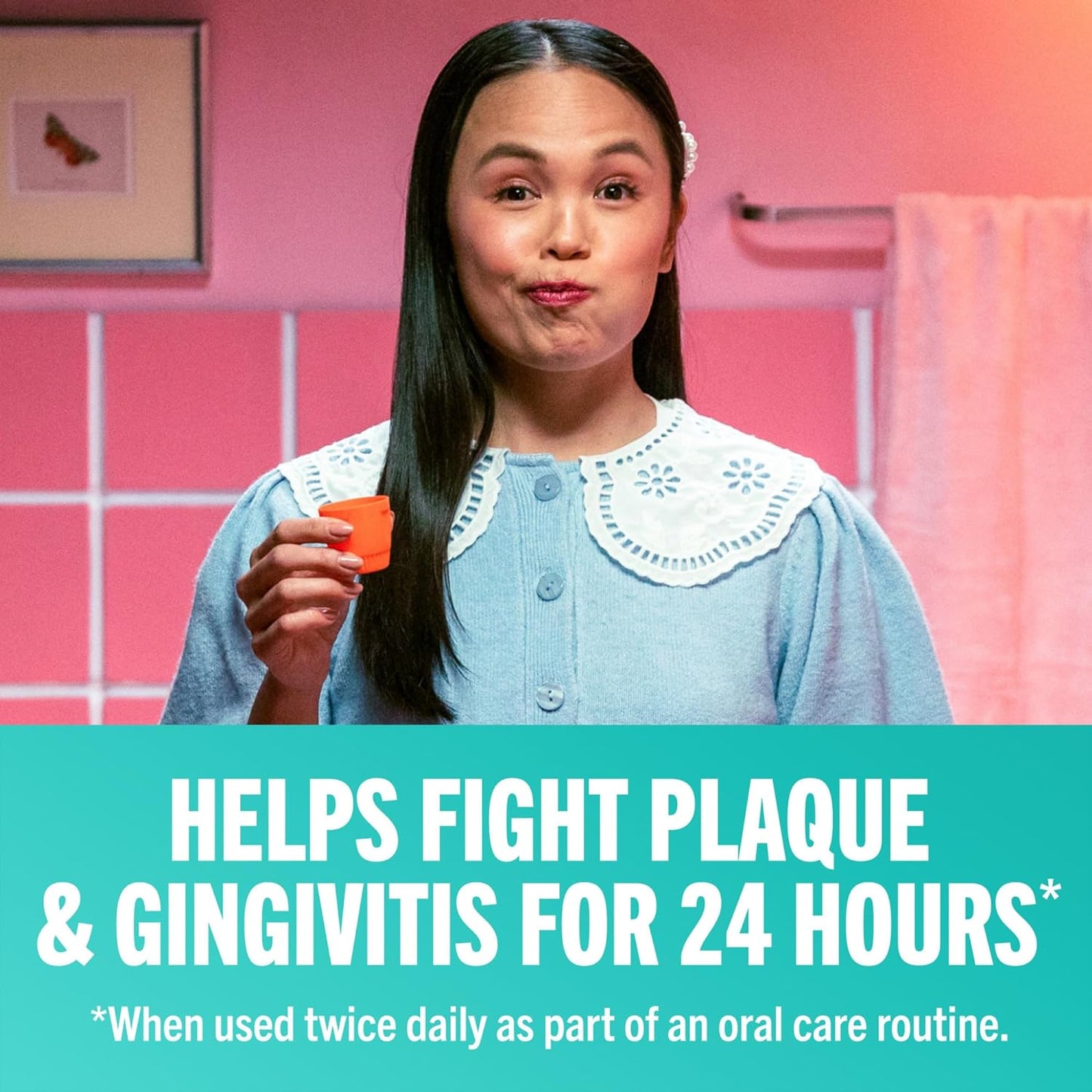 Woman in a bright pink bathroom gargles while holding an orange TheraBreath Oral Rinse cap. Under her image is written "Helps fight plaque & gingivitis for 24 hours when use twice daily as part of an oral care routine."