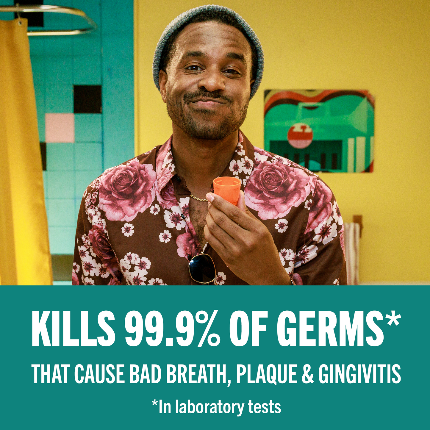 Man smiling looking at the mirror while gargling TheraBreath Oral Rinse that kills 99.9% of germs that cause bad breath, plaque & gingivitis. In laboratory tests.