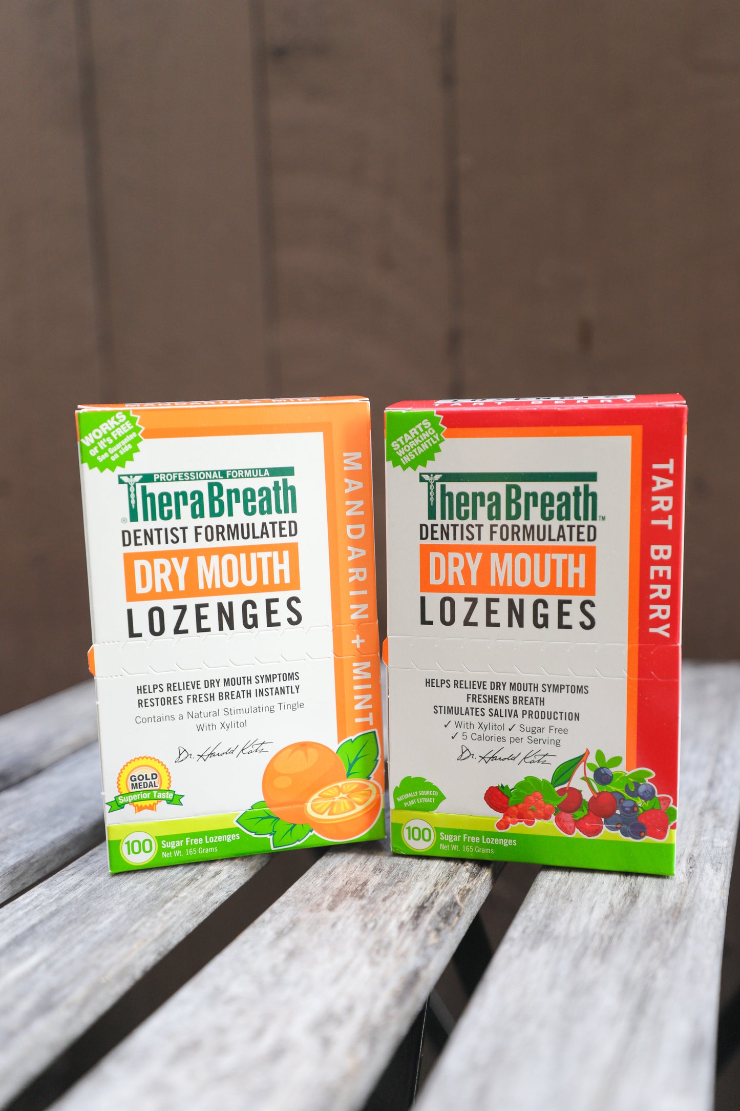Boxes of TheraBreath Dry Mouth Lozenges in Tart Berry and Mandarin Mint sit on wooden slats.