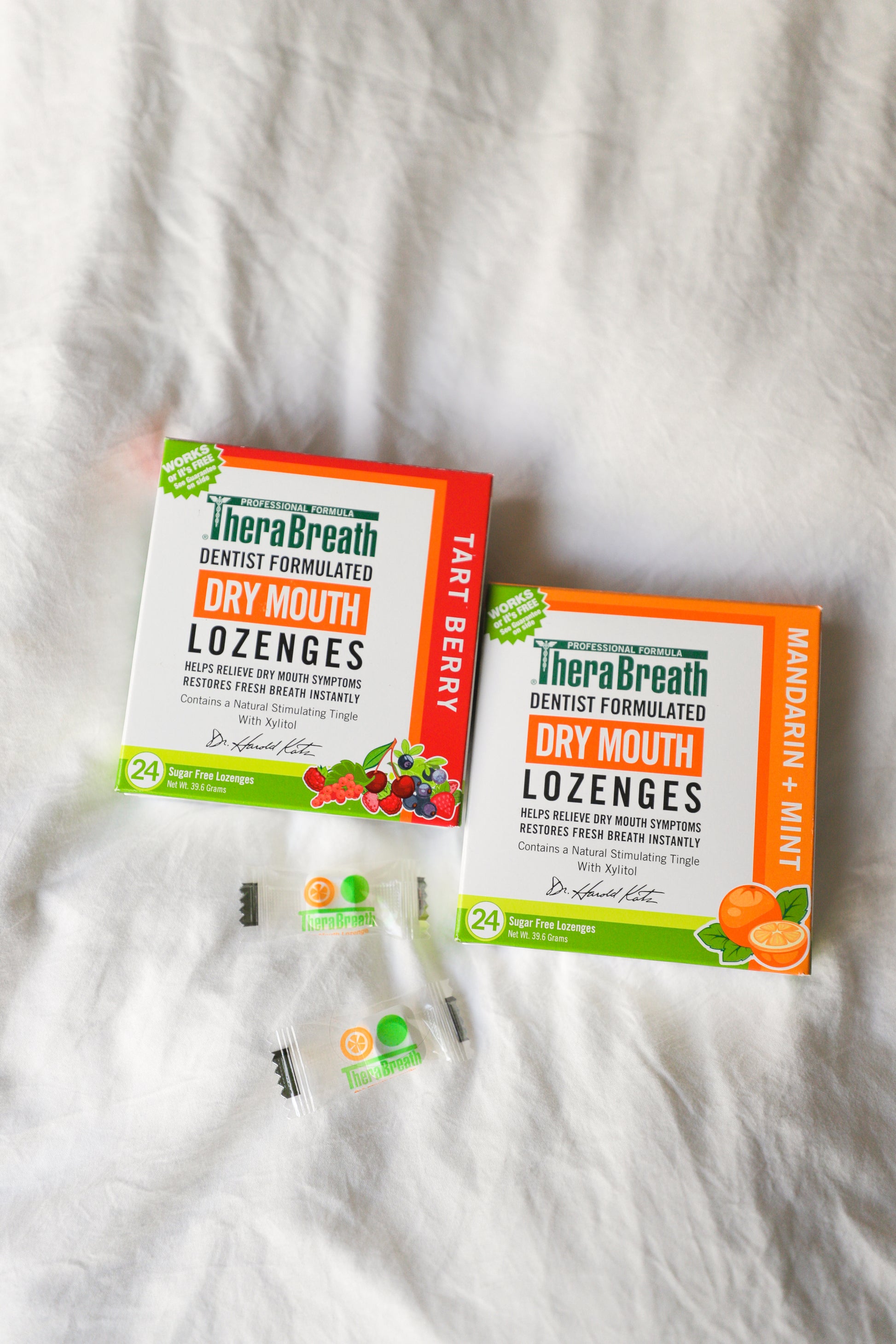 Boxes of TheraBreath Dry Mouth Lozenges in Tart Berry and Mandarin Mint sit on a white cover.