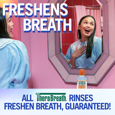 Smiling woman in front of a mirror with “Freshens Breath” and “All TheraBreath rinses freshen breath, guaranteed!”