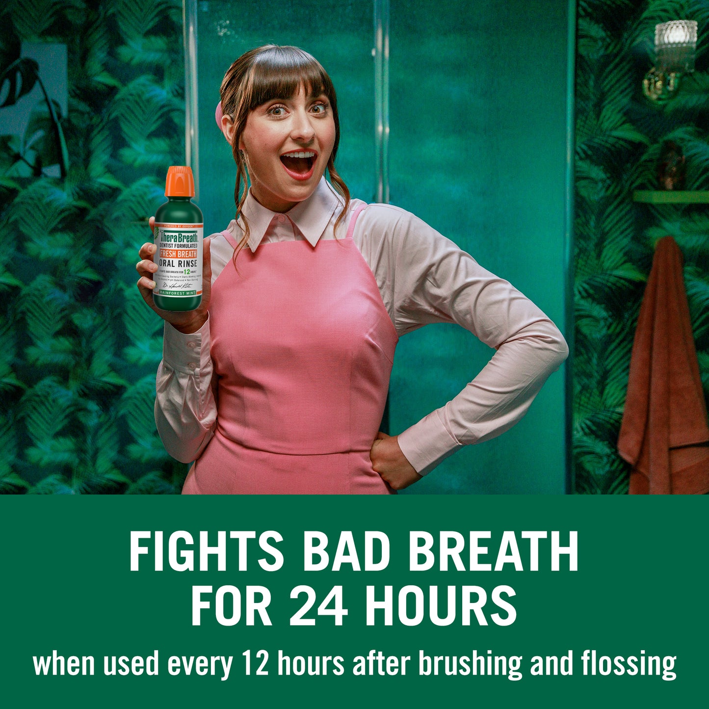 "Fights bad breath for 24 hours when used every 12 hours after brushing and flossing" this image states, with a woman holding a bottle of TheraBreath Fresh Breath Oral Rinse in Rainforest Mint 
