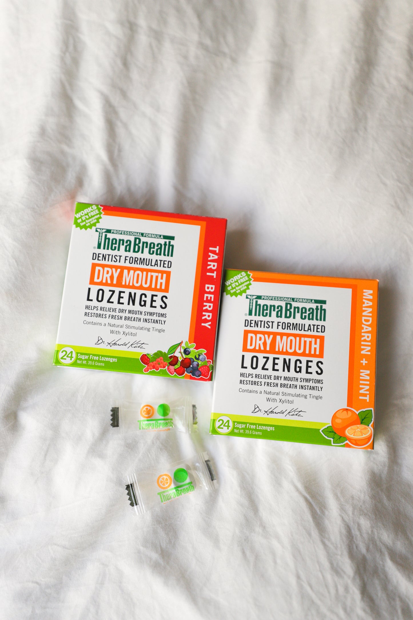 Boxes of TheraBreath Dry Mouth Lozenges in Tart Berry and Mandarin Mint sit on a white cover.