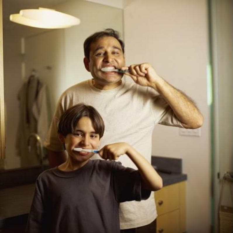 Father and son brushing teeth together